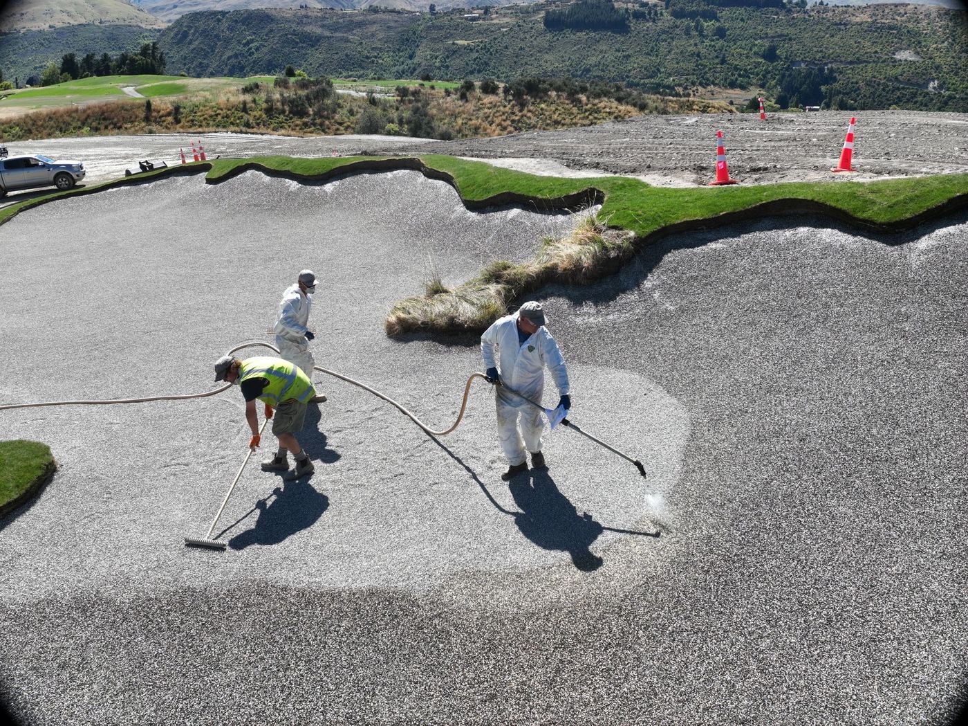 Crew spraying a bunker liner before sand goes in