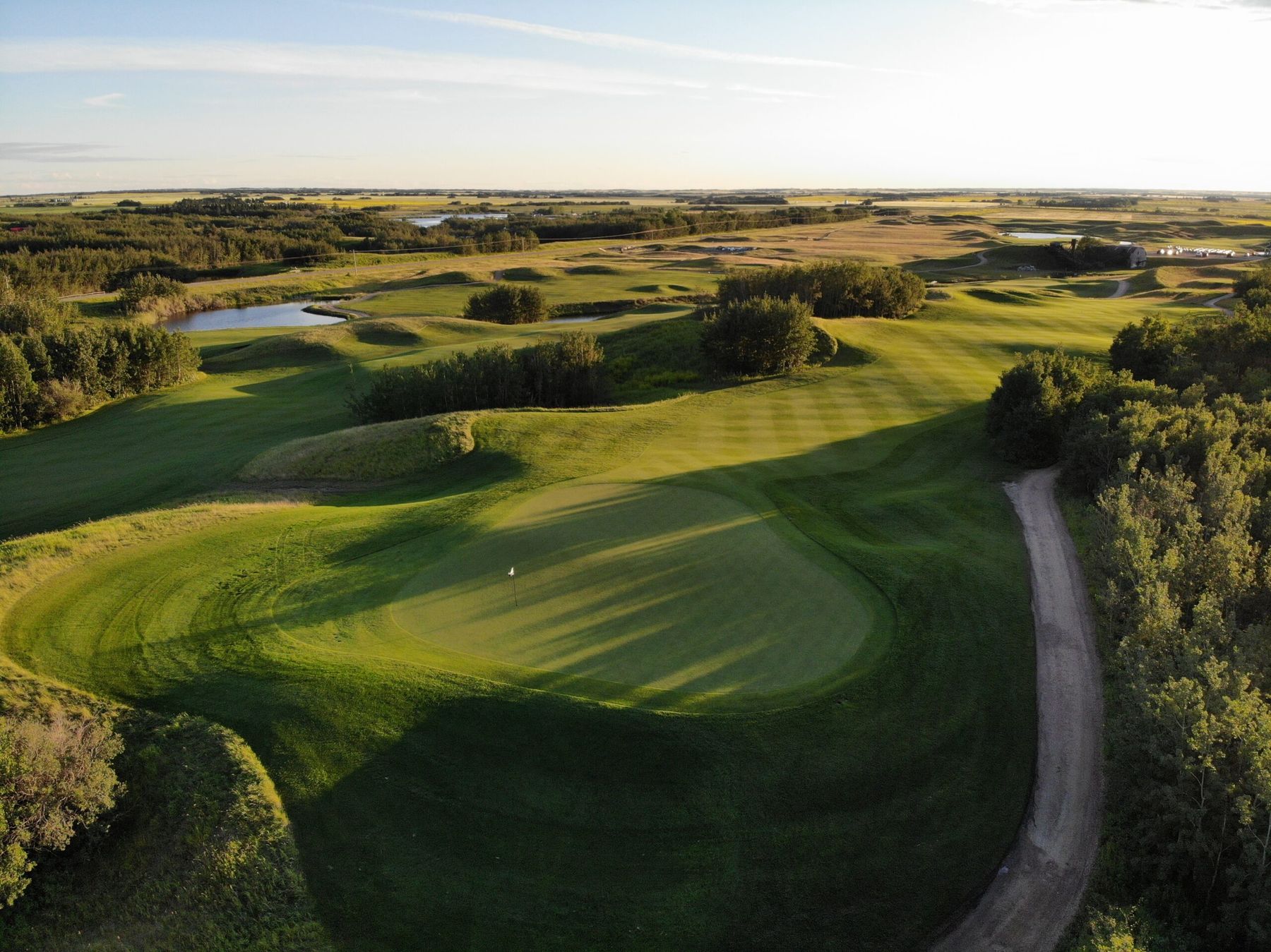 Aerial of the 12th green at Coal Creek in evening light, framed by aspen and mounding