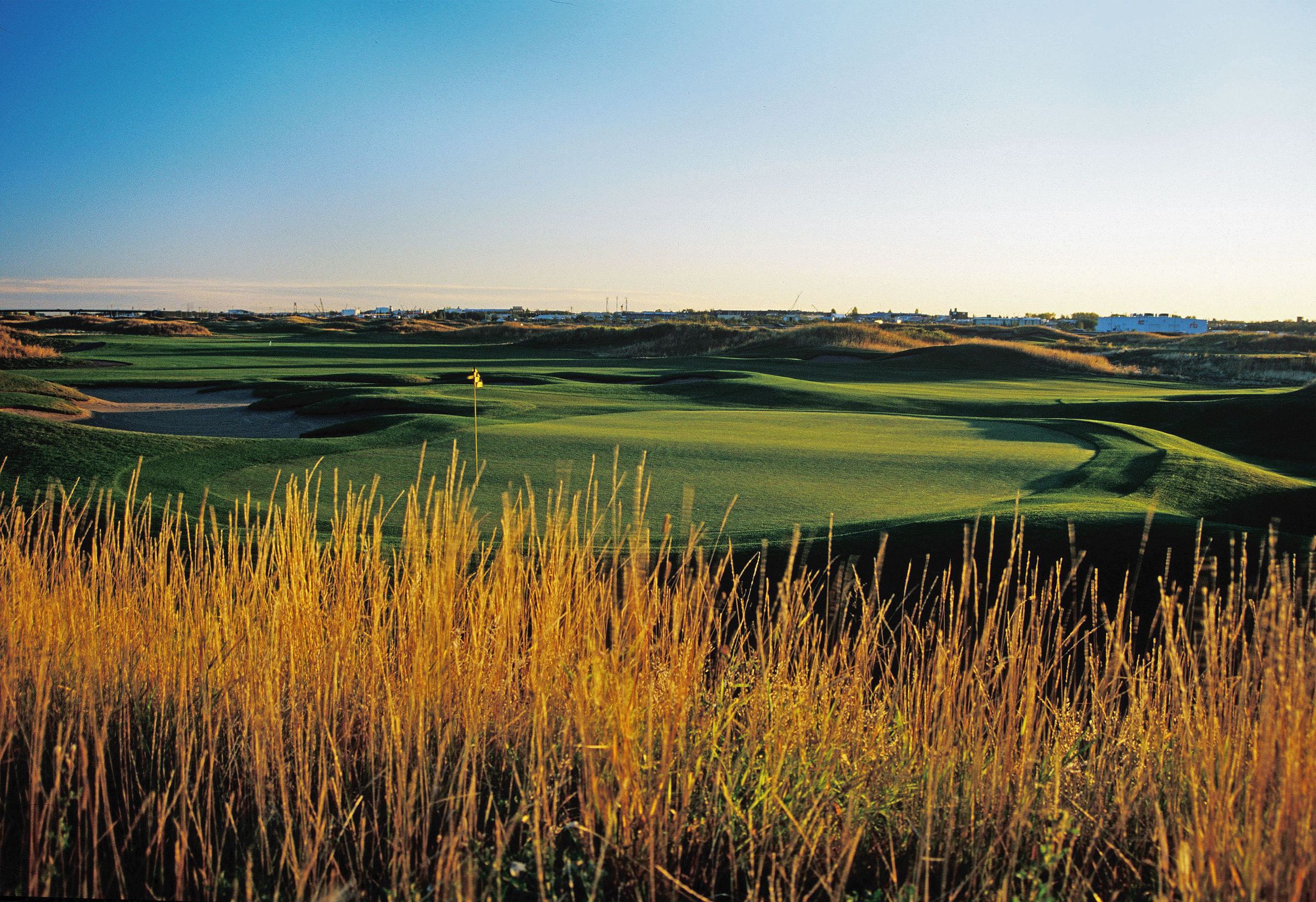 Sunrise over a green at RedTail Landing with native grasses in the foreground